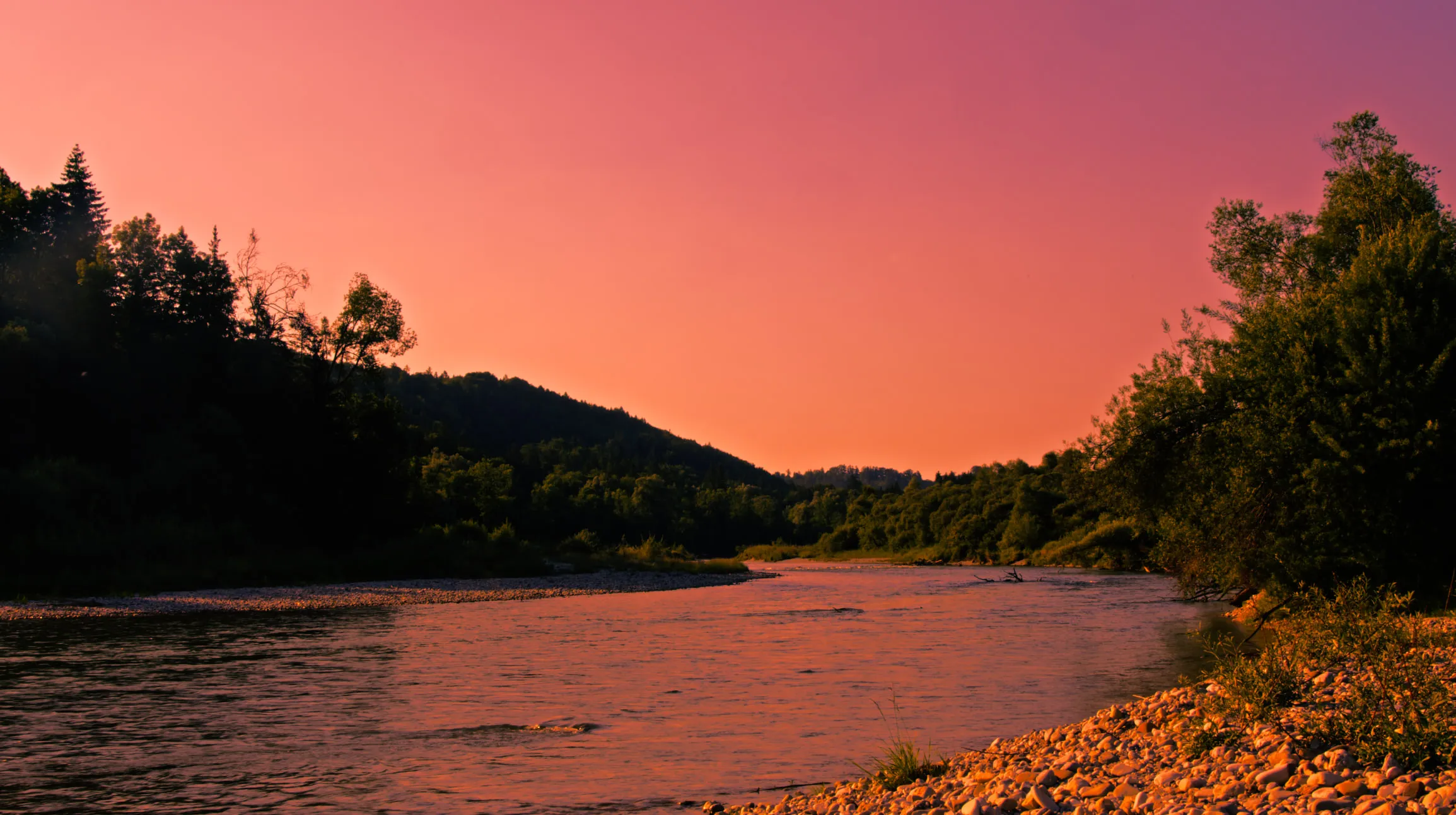 Fluss in der Isarlandschaft bei Sonnenuntergang unter rot gefärbtem Himmel