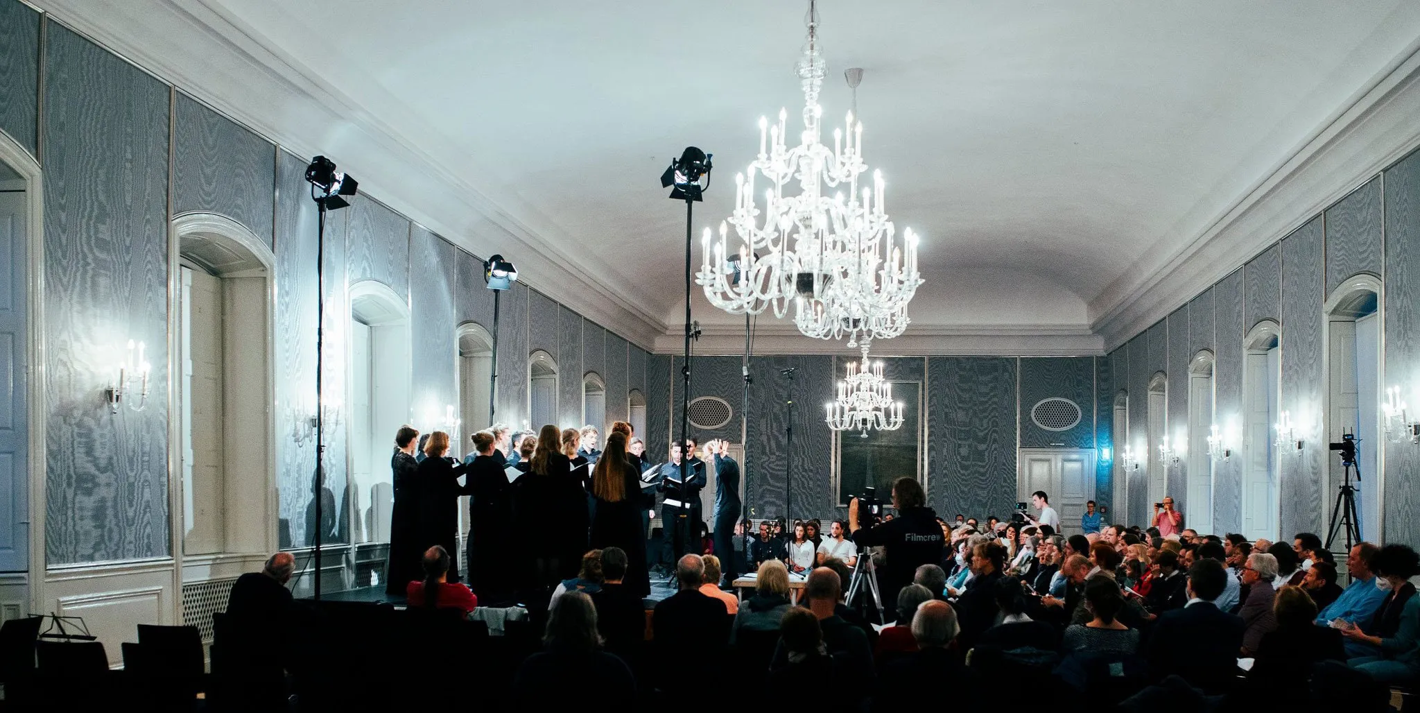 Konzert im Hubertussaal mit Kronleuchtern, Chor und Publikum