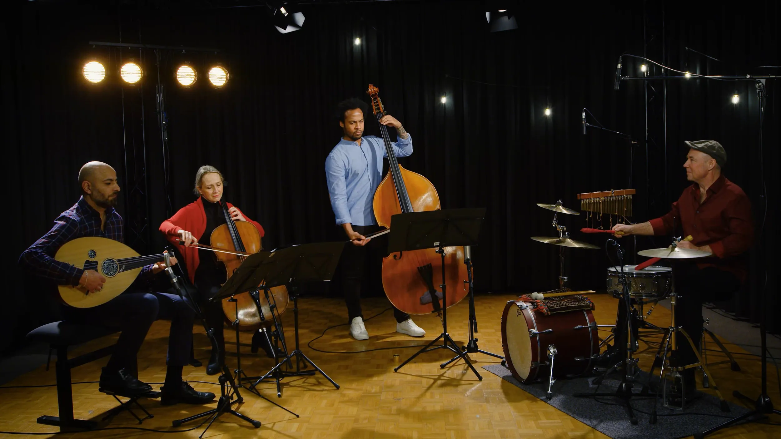 Das Ensemble spielt im Studio vor einer Reihe warmer Lampen