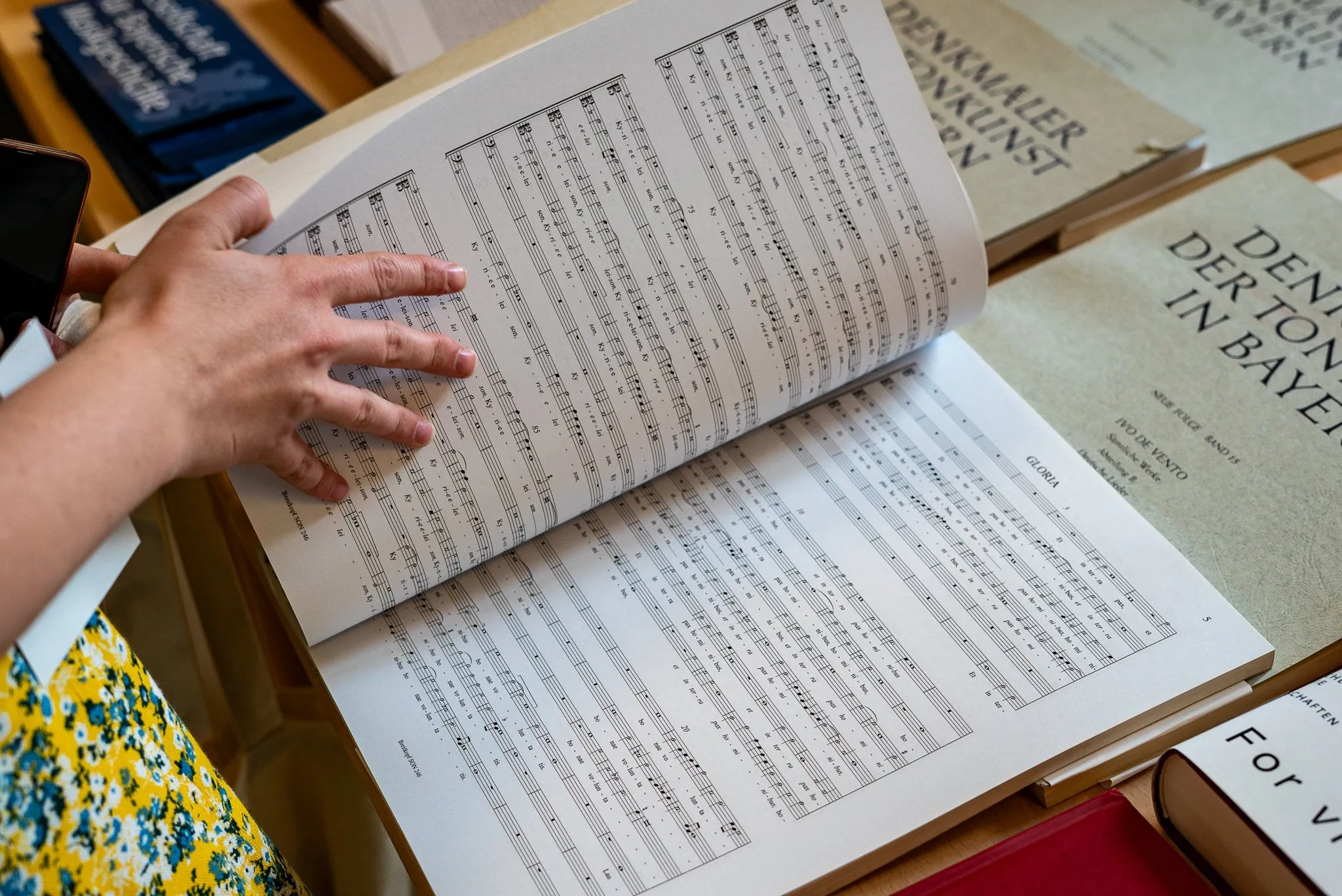 Hand auf einem aufgeschlagenen Notenband in einer Bibliothek