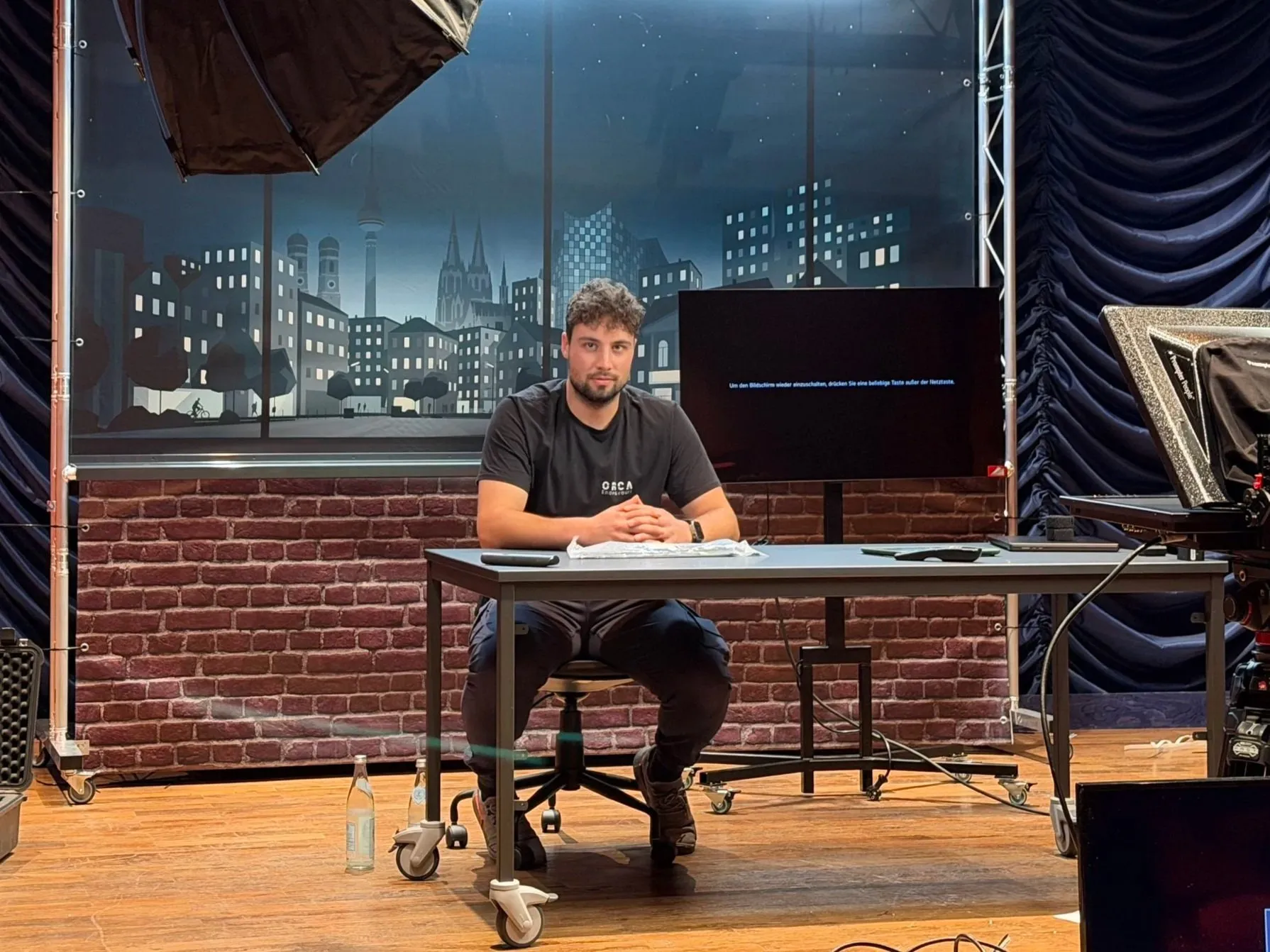 Mann sitzt am Moderationstisch im Fun-Facts-Studioset