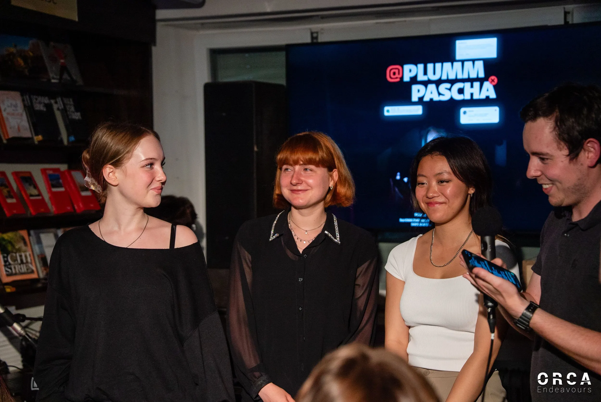 Vier Personen stehen vor einem Bildschirm mit dem Titel „Plumm Pascha“