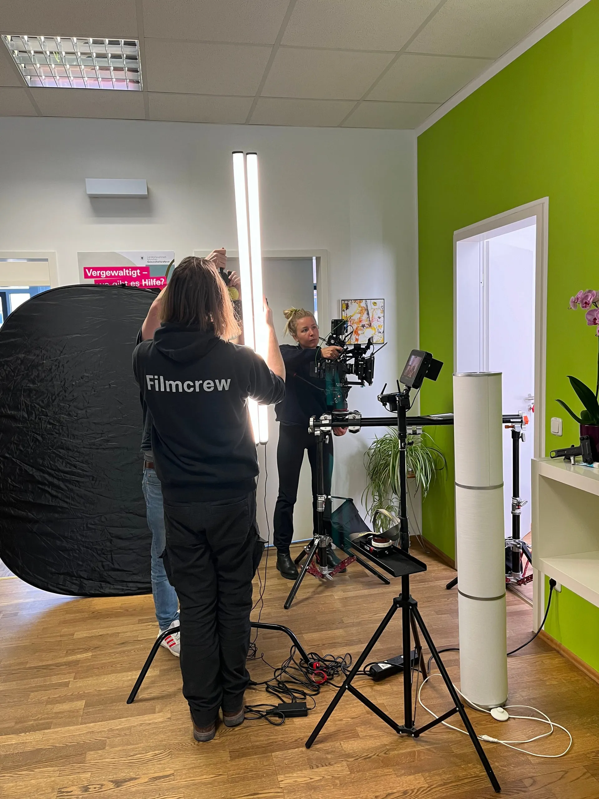 Filmcrew mit Kamera und Reflektor beim Dreh in einer Beratungsstelle