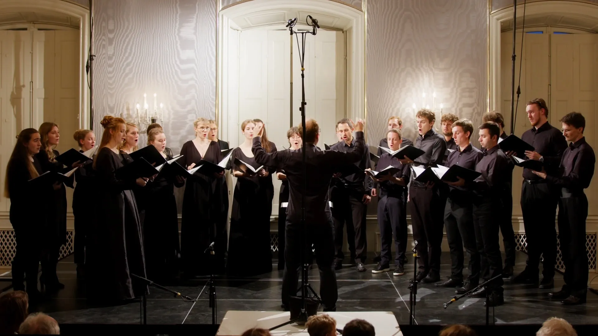 Der Kammerchor ARETHAS ensemble singt in einem hellen Saal unter Leitung des Dirigenten