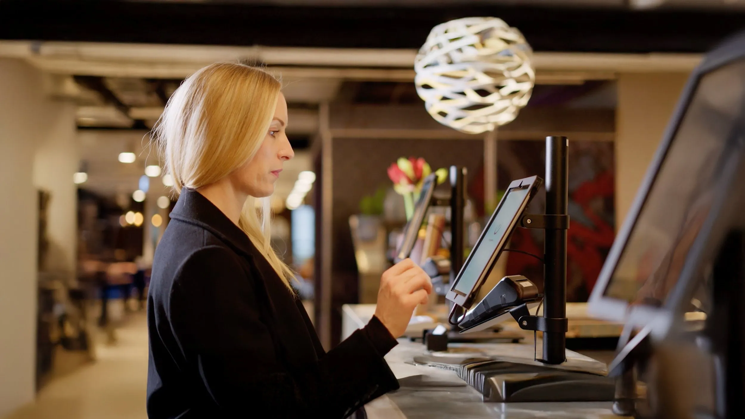Rezeptionistin mit blonden Haaren bedient ein Tablet an der Hotelrezeption