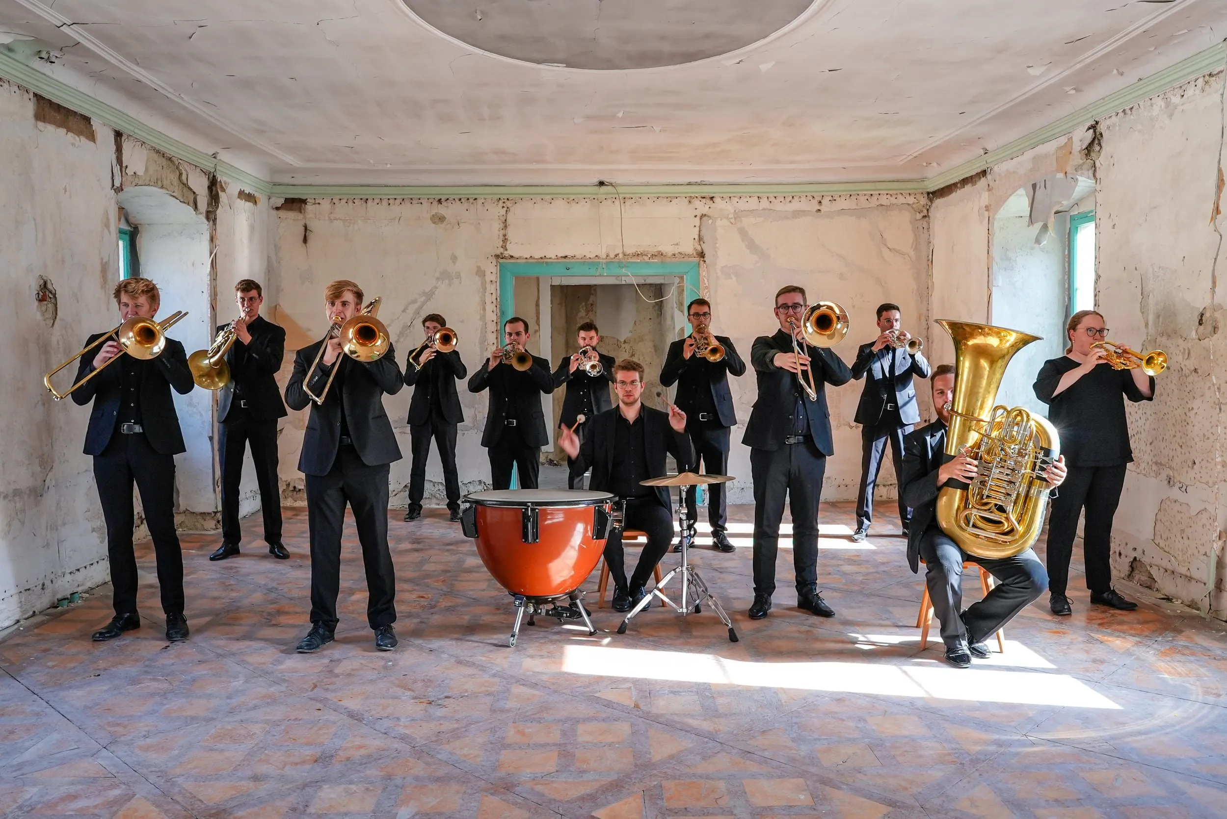 Blechbläserensemble mit Pauken und Tuba in einem verfallenen Saal