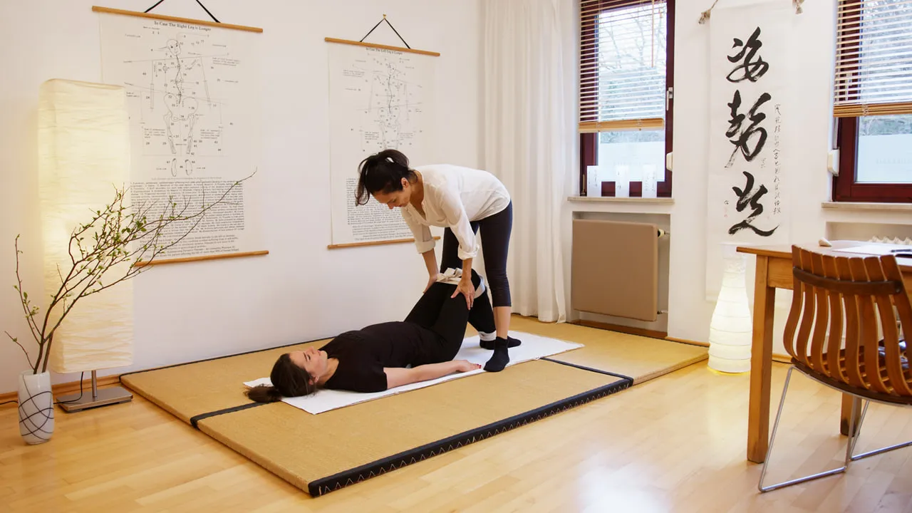 Shiatsu-Behandlung in einem hellen Raum mit japanischer Kalligrafie