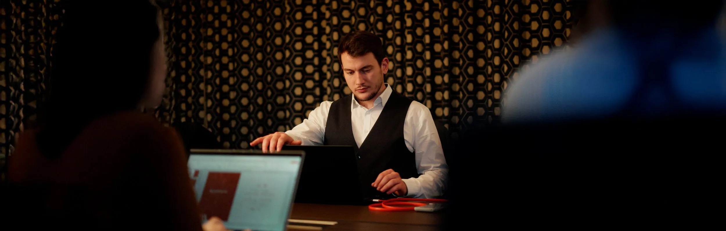 Mann im Anzug arbeitet konzentriert am Laptop in einem dunklen Hotelfoyer