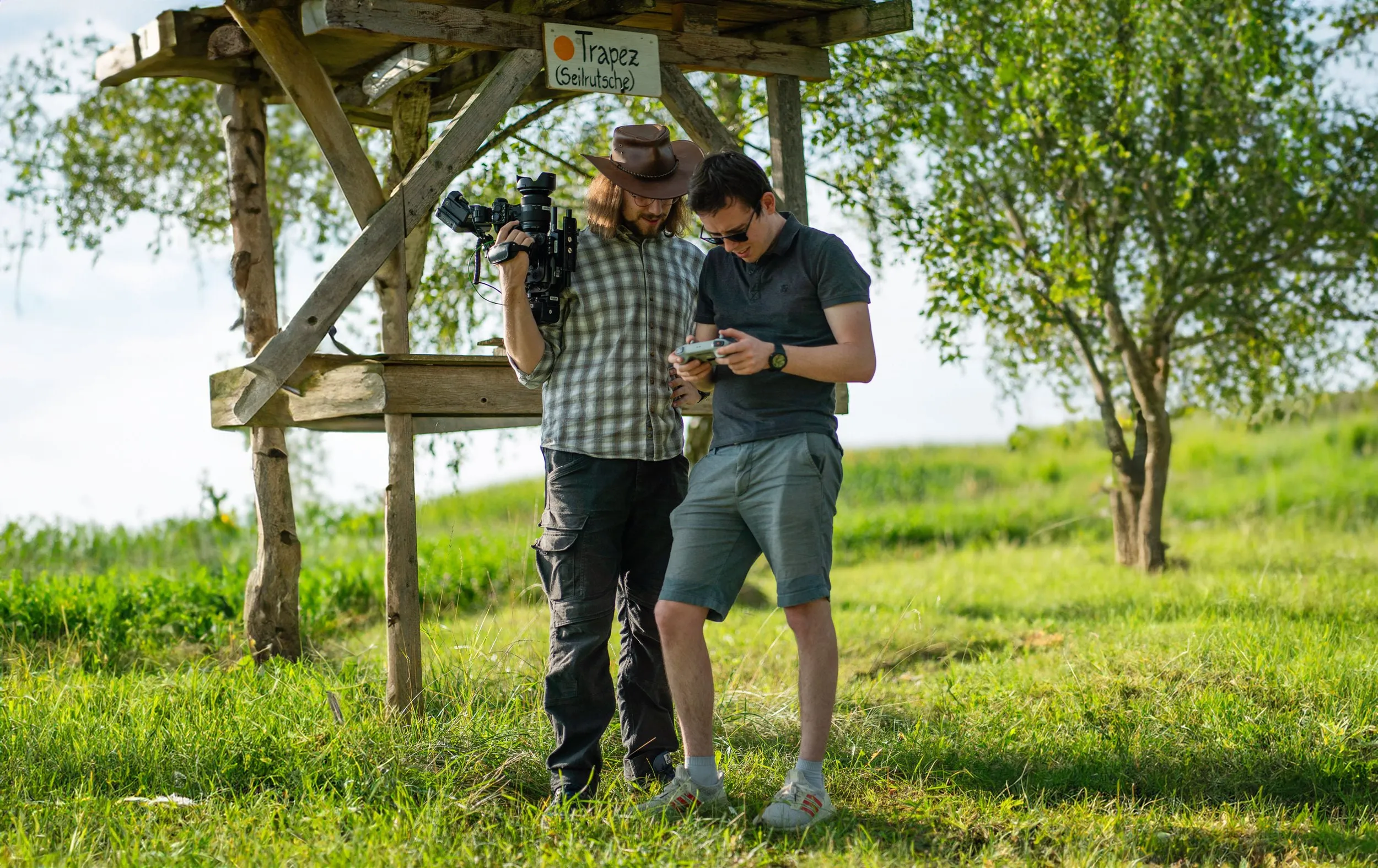Filmcrew bespricht eine Einstellung unter einem Hochsitz auf einer Wiese