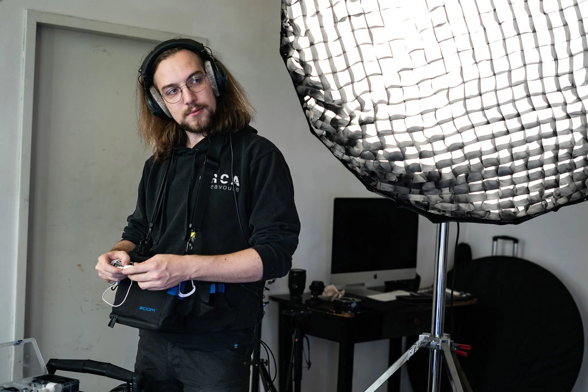 Teammitglied mit Kopfhörern vor einem großen Lichtschirm im Studio