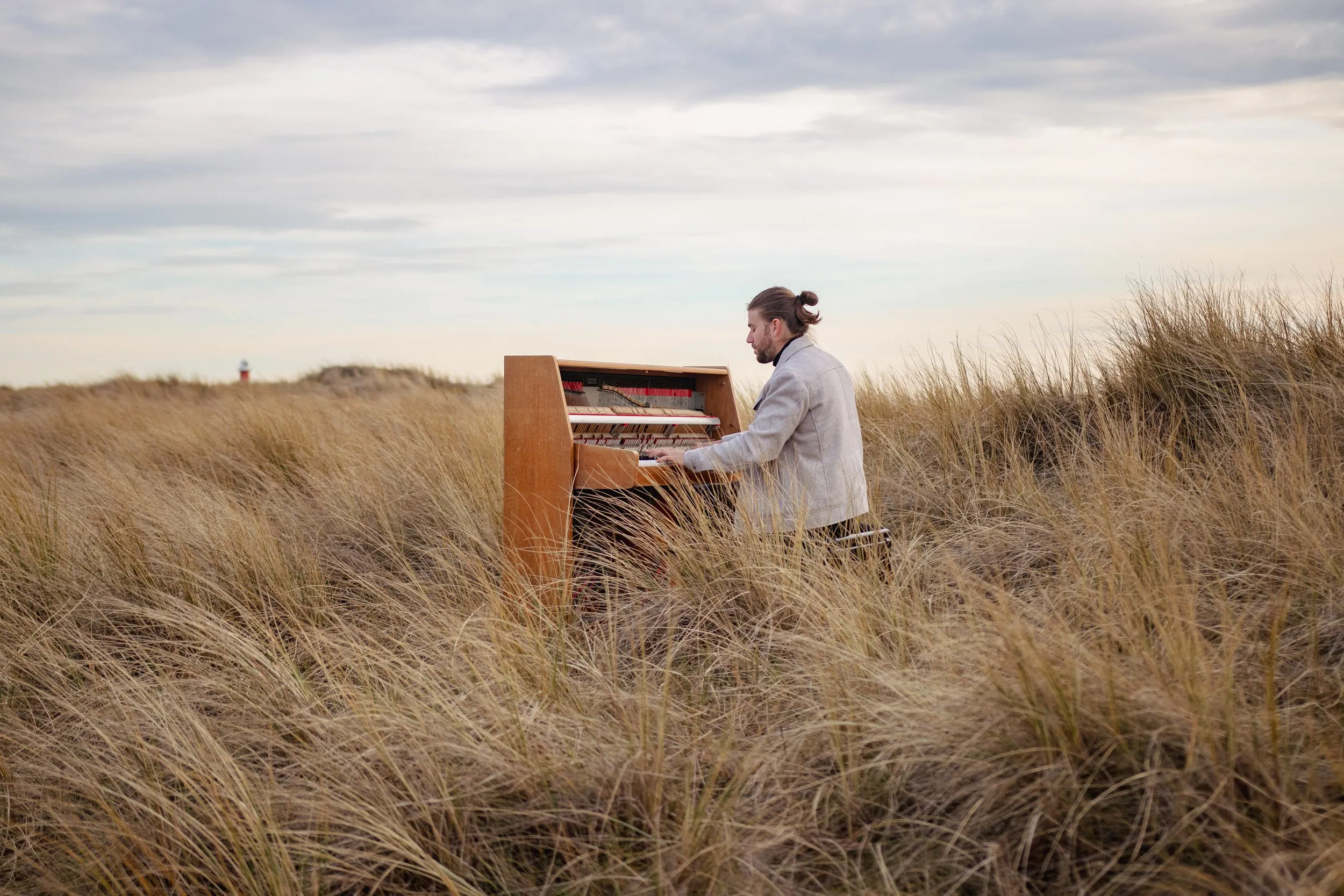 Pianist spielt an einem Klavier inmitten von Dünengras